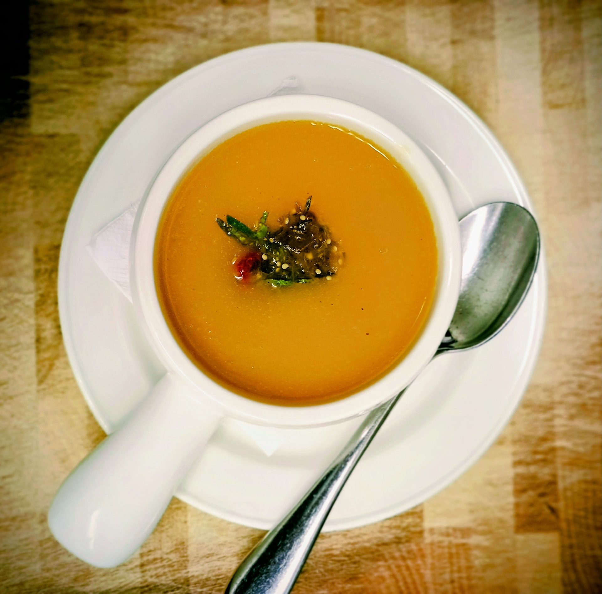 A bowl of golden soup with a spoon