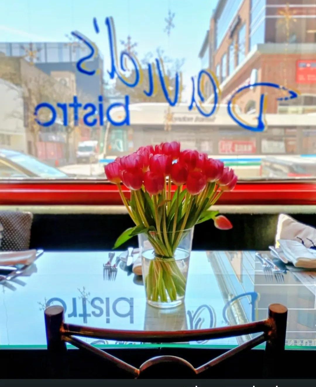 Red tulips on a window table, the bistro’s name painted on the glass